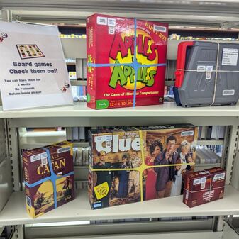 Just a few board games at the library, including Apples to Apples, Settlers of Catan, Clue, and exploding Kittens