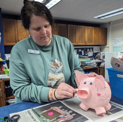 Megan Daumen painting a paper mache piggy bank